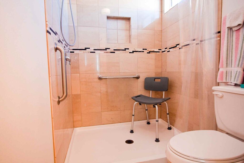 reforma baño para personas mayores con asiento abatible e inodoro con apoyos laterales.